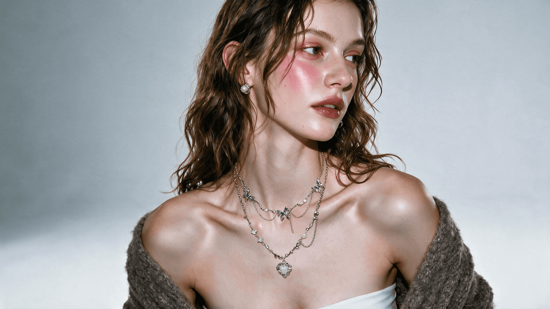 Model wearing layered silver necklaces and pearl earrings
